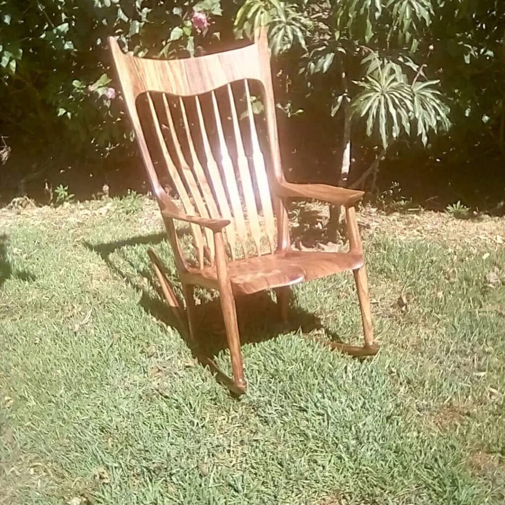 “Painted sculpted rocking chair with a dark layered finish displayed beside a Christmas tree.”